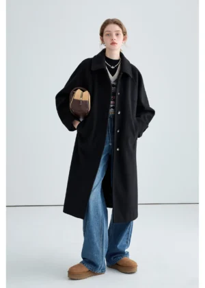 Black long insulated streetwear overcoat styled with wide-leg jeans and shearling loafers in a three-quarter front view