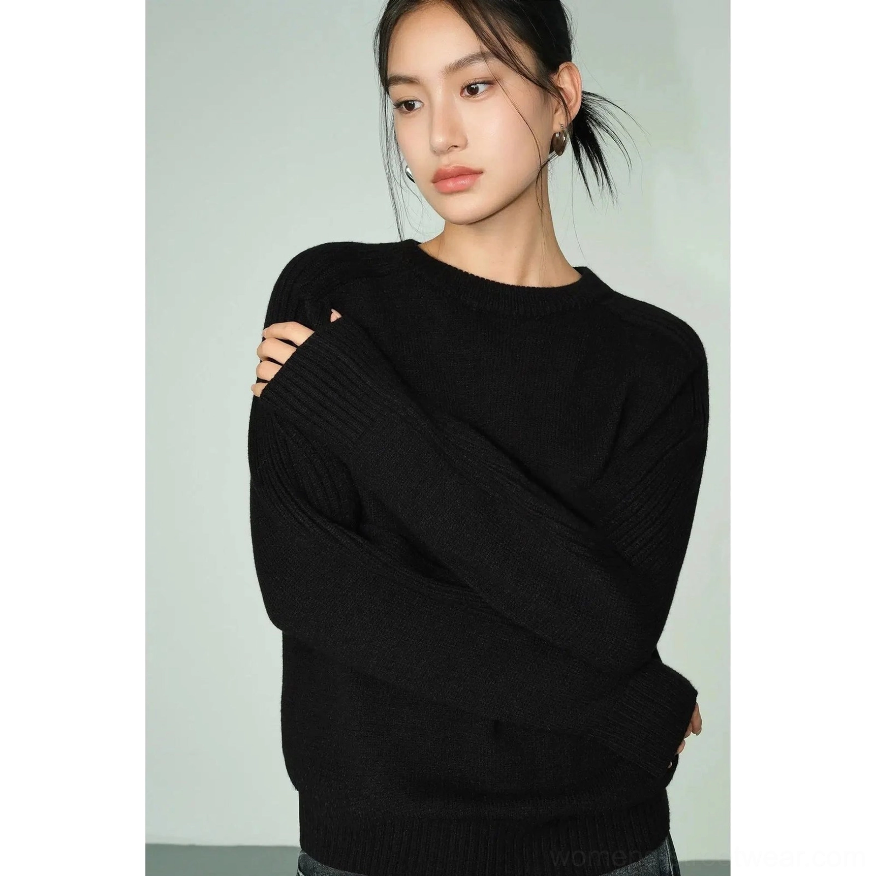 Three-quarter side view of black loose crew neck sweater with long sleeves and minimalist Korean streetwear design