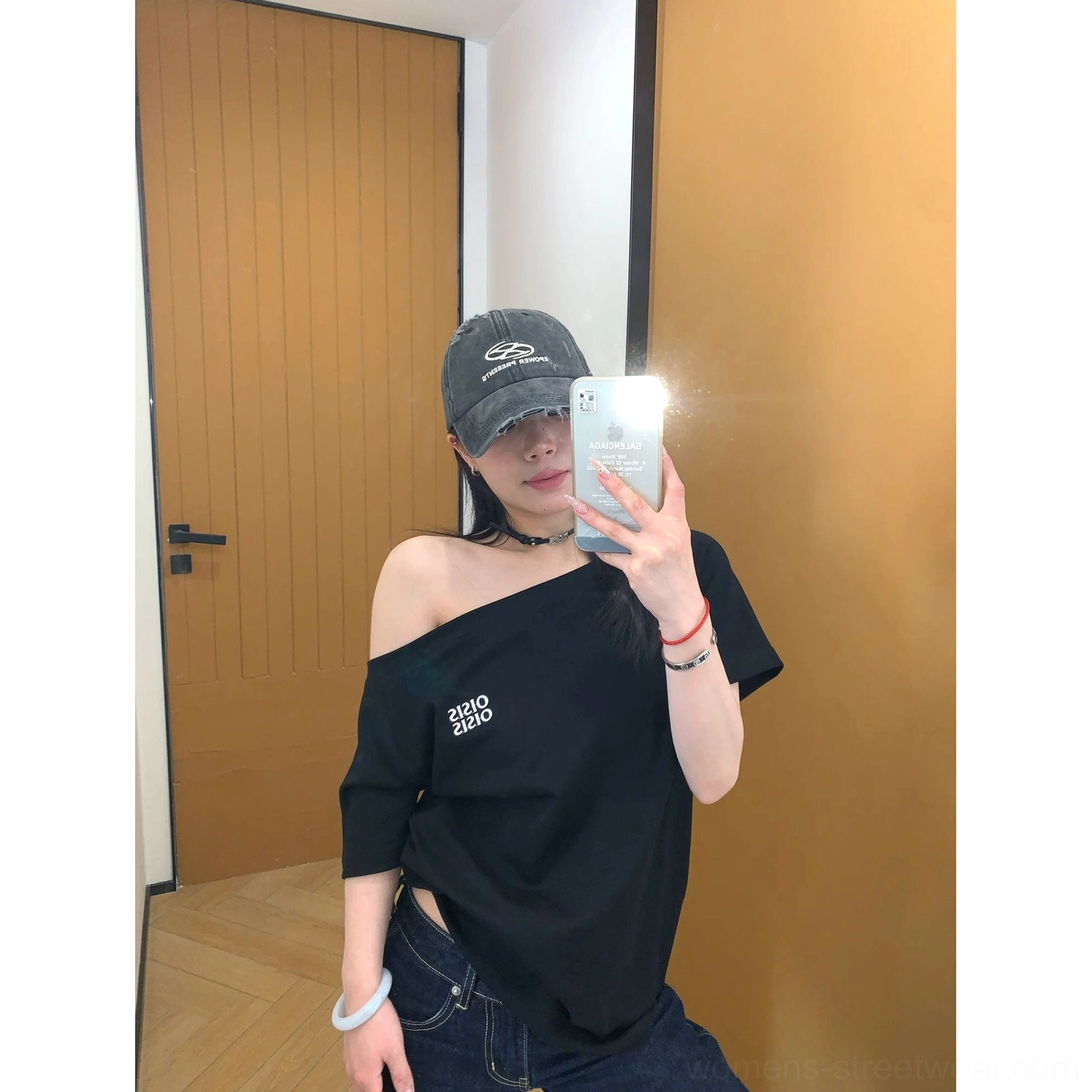 Front view of a black loose-fit one-shoulder logo tee with a small white chest print and dark jeans