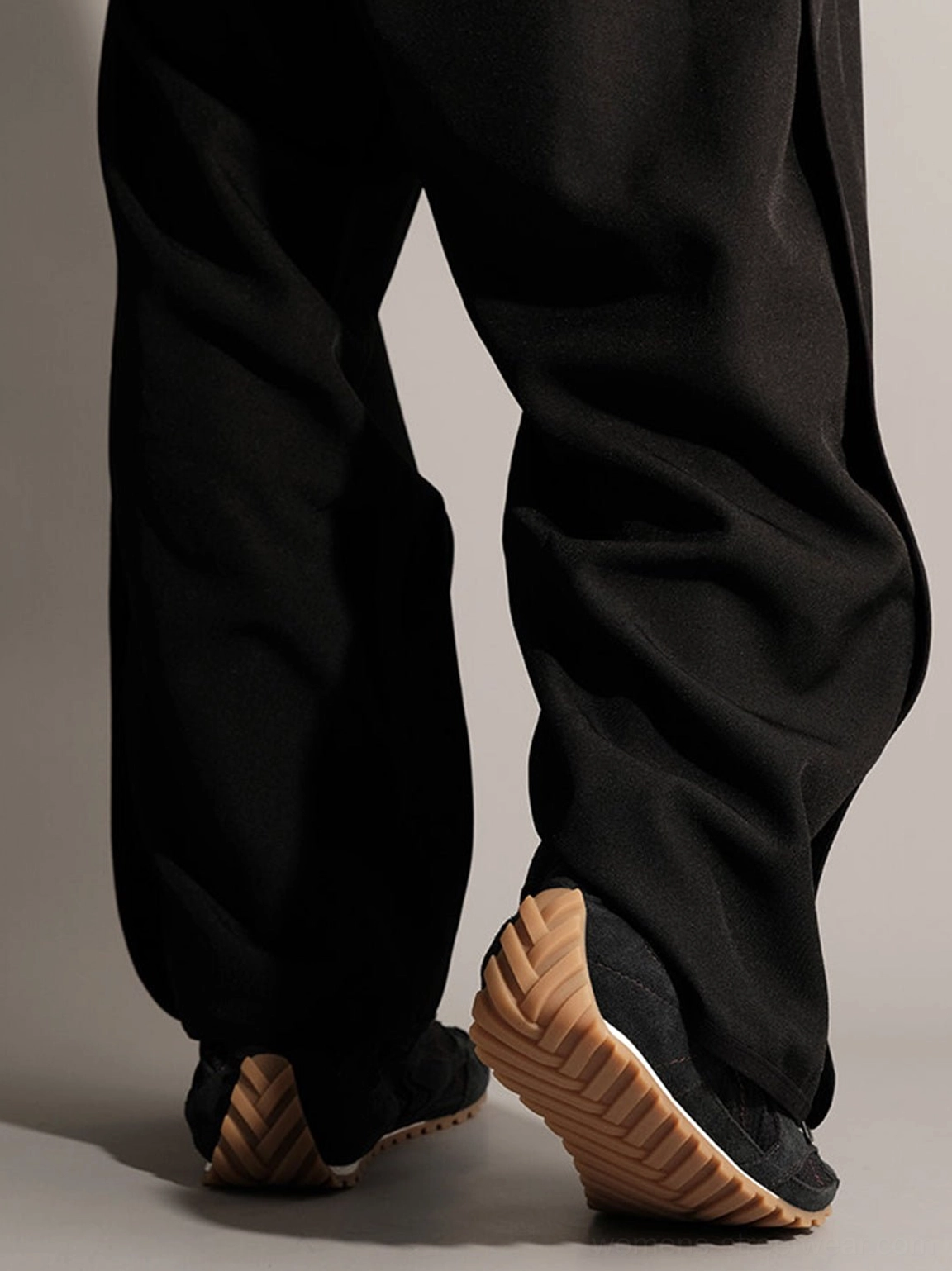 Bottom rear view of black low-profile trainers showing thick ridged gum rubber outsole