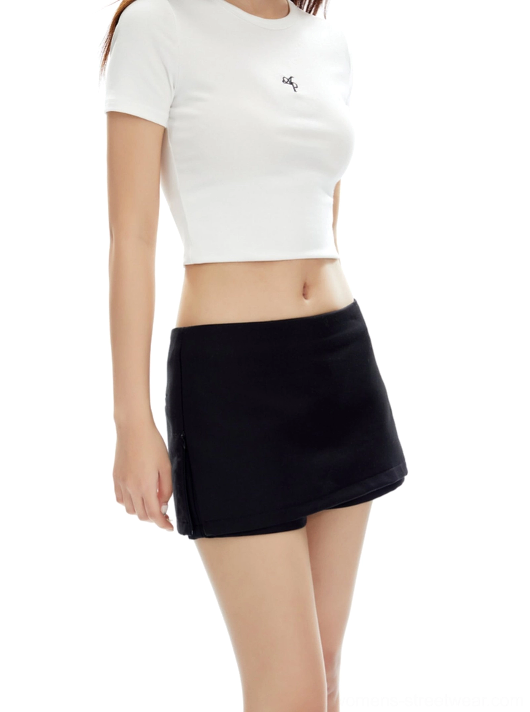 Side view of a black low-rise mini skirt with smooth suiting texture and cropped white minimalist top