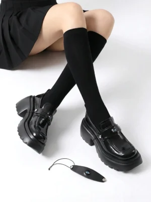 Black chunky lug-sole platform loafers styled with pleated mini skirt and knee-high socks for Korean streetwear fashion