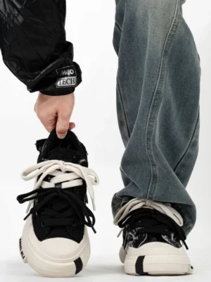 Black marble-effect canvas platform sneakers with contrasting dual-tone laces and cream chunky rubber sole shown in a close-up streetwear outfit