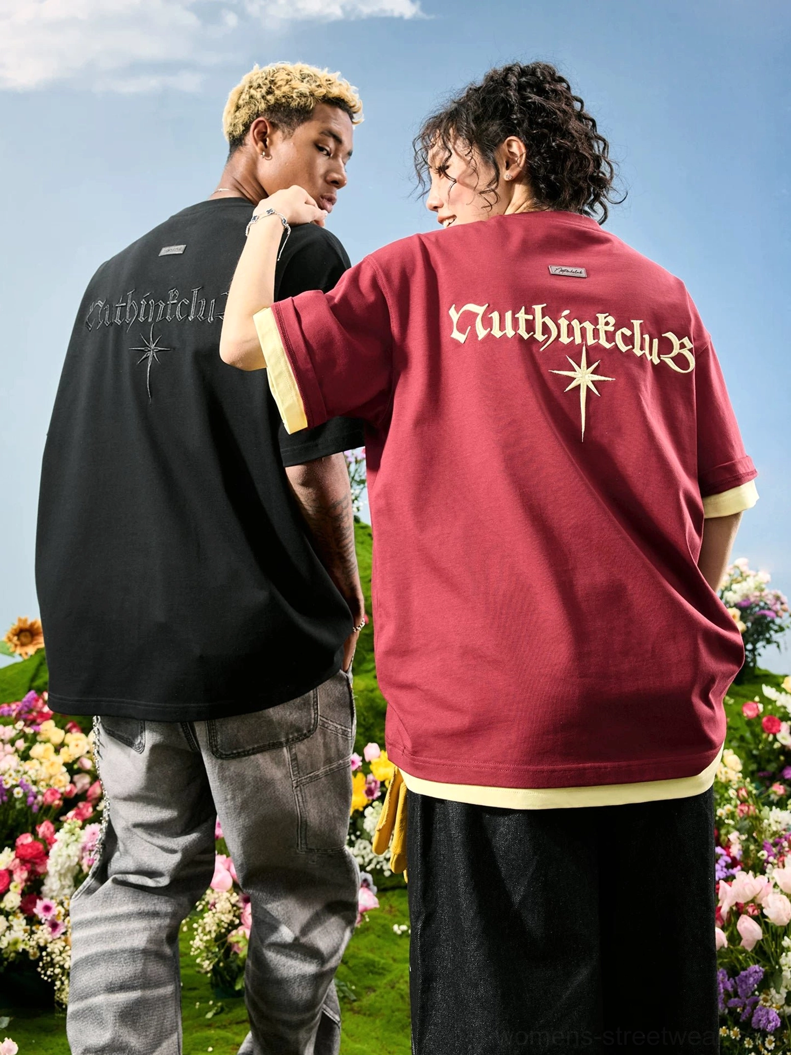 Two models wearing oversized embroidered streetwear T-shirts in black and maroon with Gothic back graphics and layered faux two-piece details