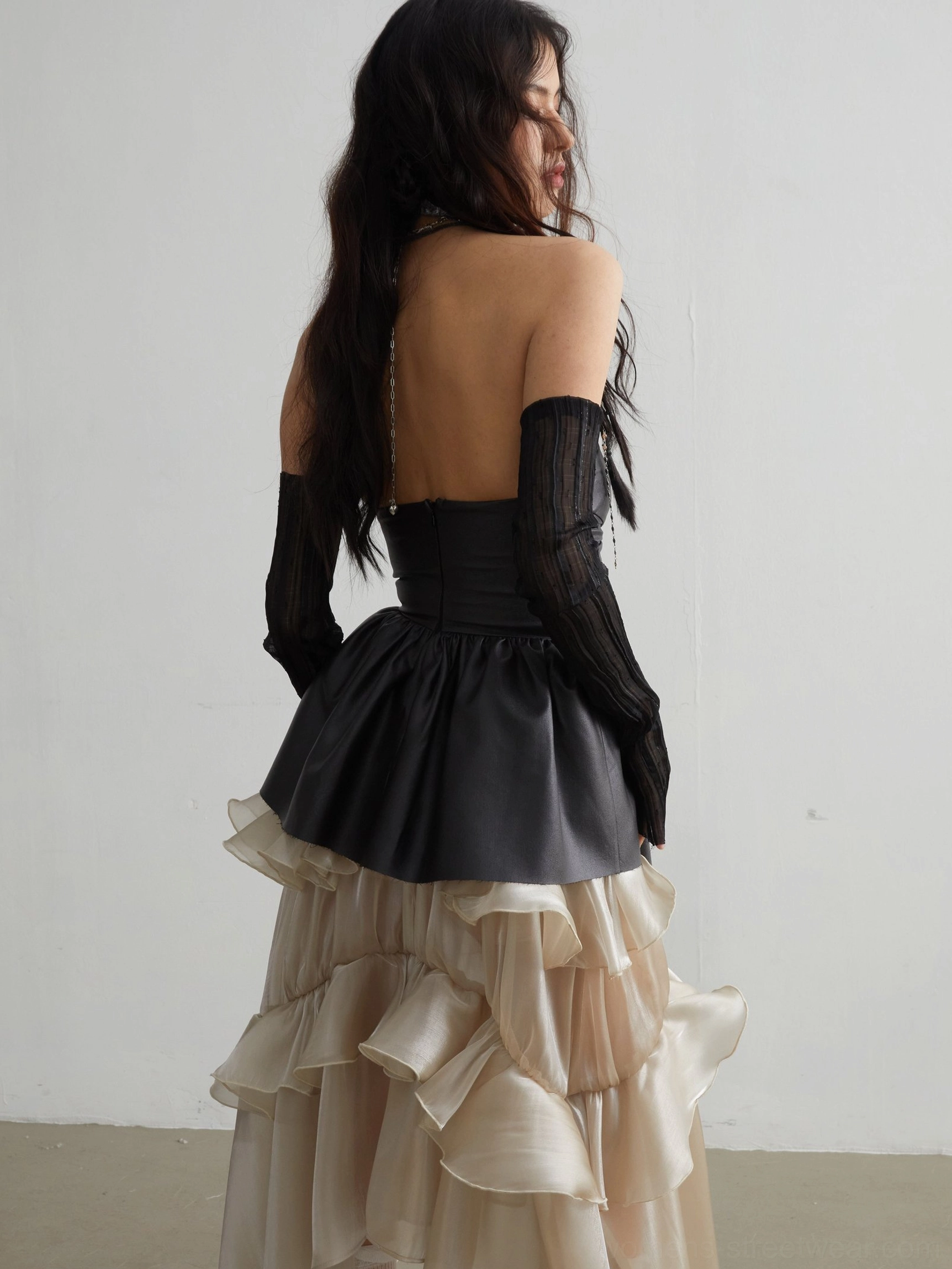 Back view of black matte PU ruffled corset crop top showing low back silhouette and asymmetric ruffle detail