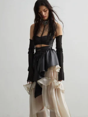 Black ruffled matte PU corset crop top front view with lace-up detail and asymmetric peplum in an editorial gothic outfit