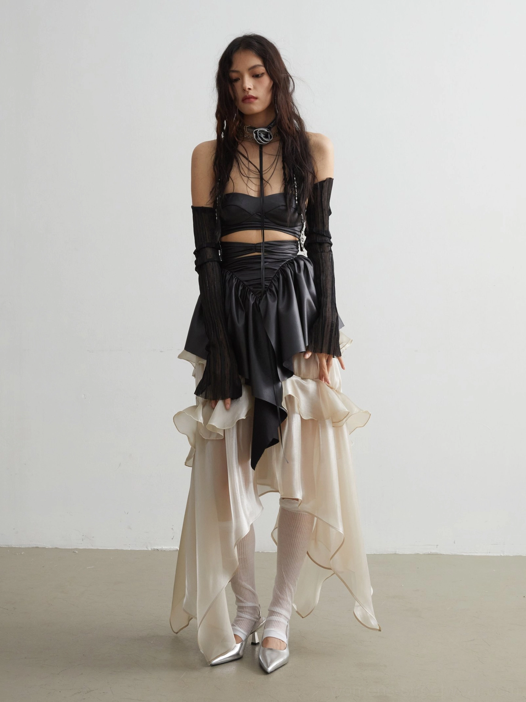 Black matte PU ruffled crop top right three-quarter view showing fitted corset-inspired bodice and asymmetric hem