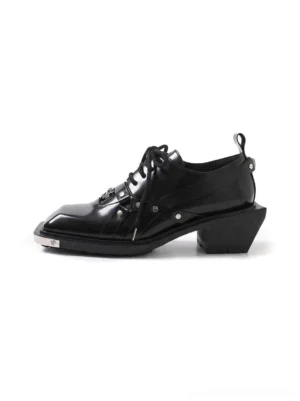Black metal toe square-toe platform derby shoe in left three-quarter studio view with glossy textured upper, buckle straps, silver hardware, and chunky block heel