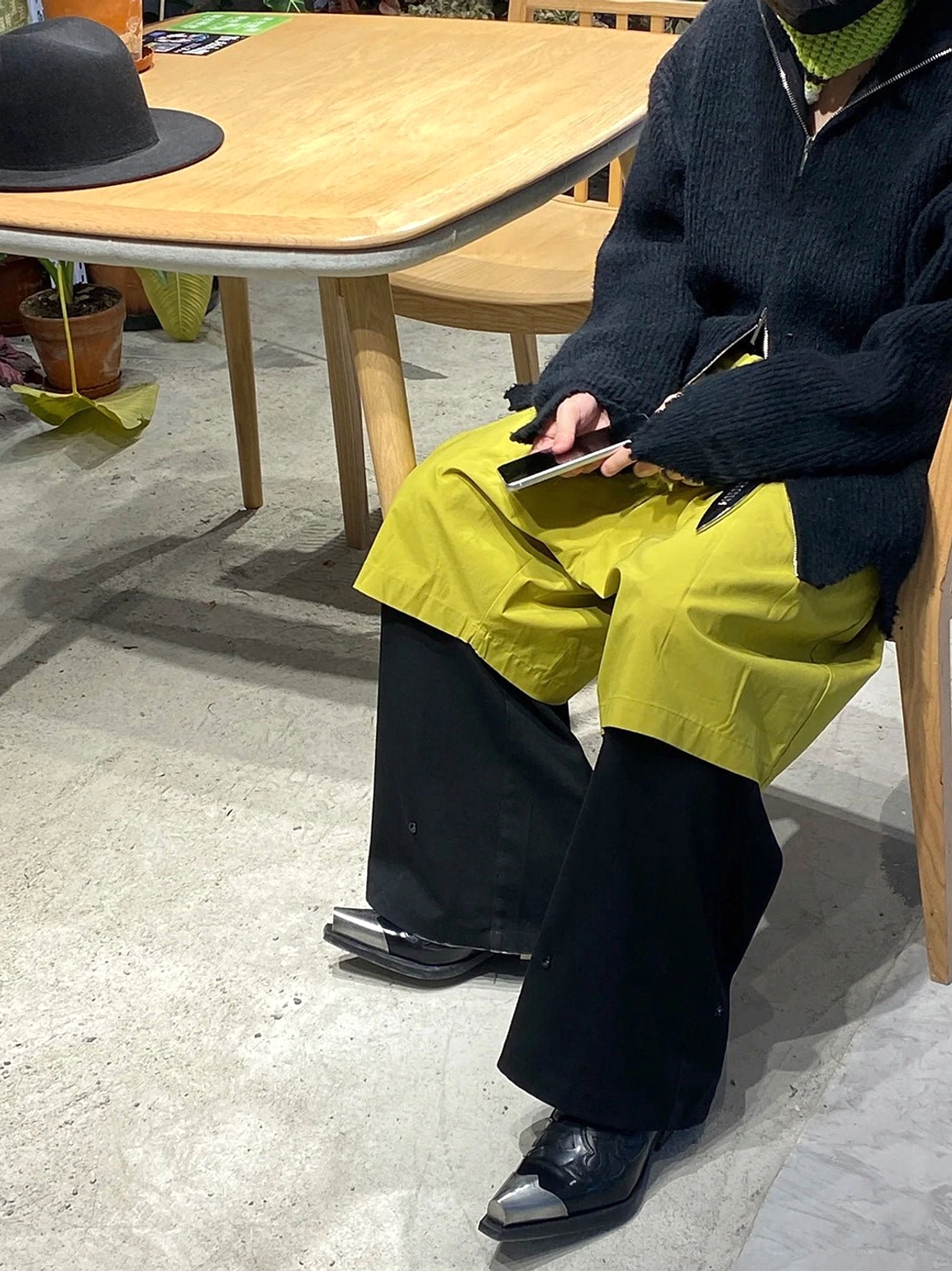 Black metallic toe Chelsea cowboy boots worn with split-tone wide-leg pants in an indoor streetwear styling scene