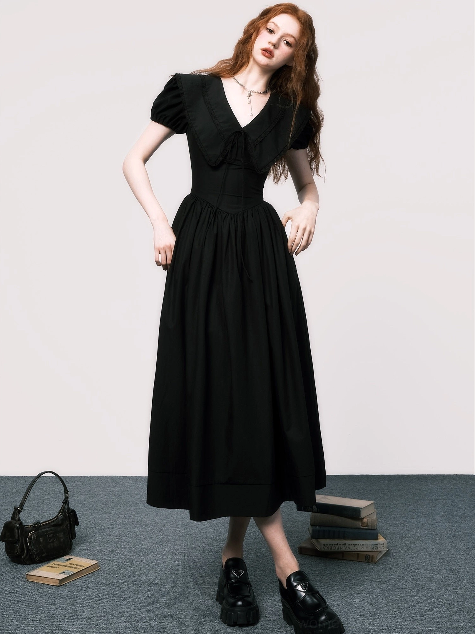 Three-quarter view of black midi dress with V-neck bow, cinched waist, puff sleeves, and elegant A-line skirt