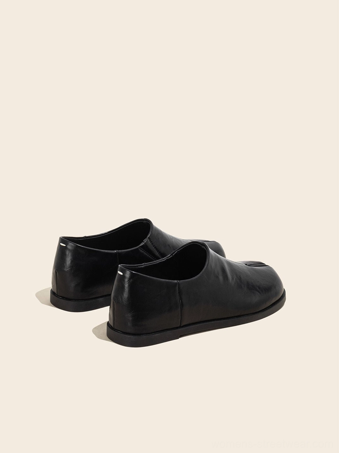Side view of black minimalist loafers highlighting the open slip-on collar, smooth upper, and low-profile flat sole