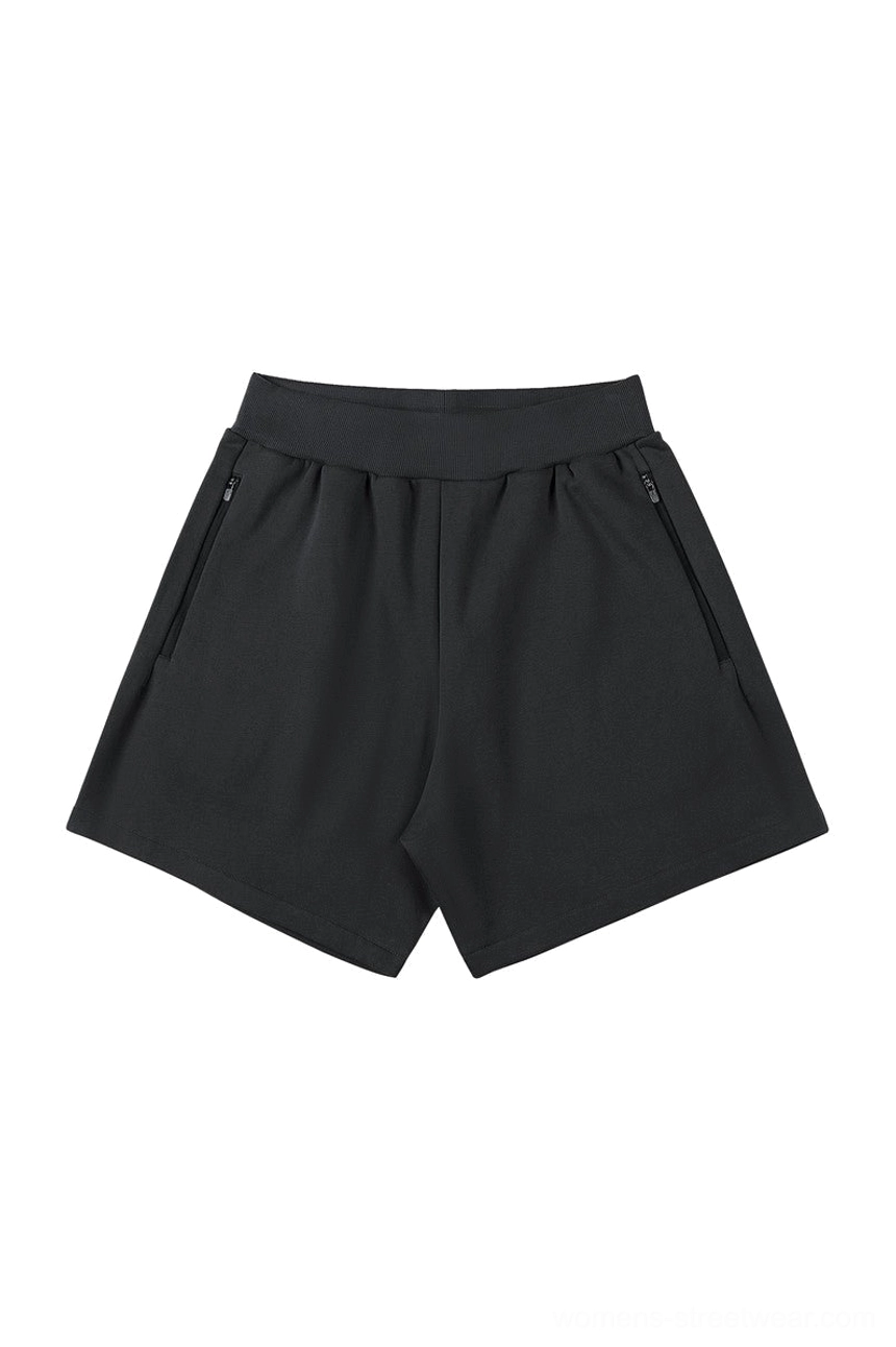 Black minimalist streetwear shorts with ribbed elastic waistband relaxed silhouette and secure side zipper pockets