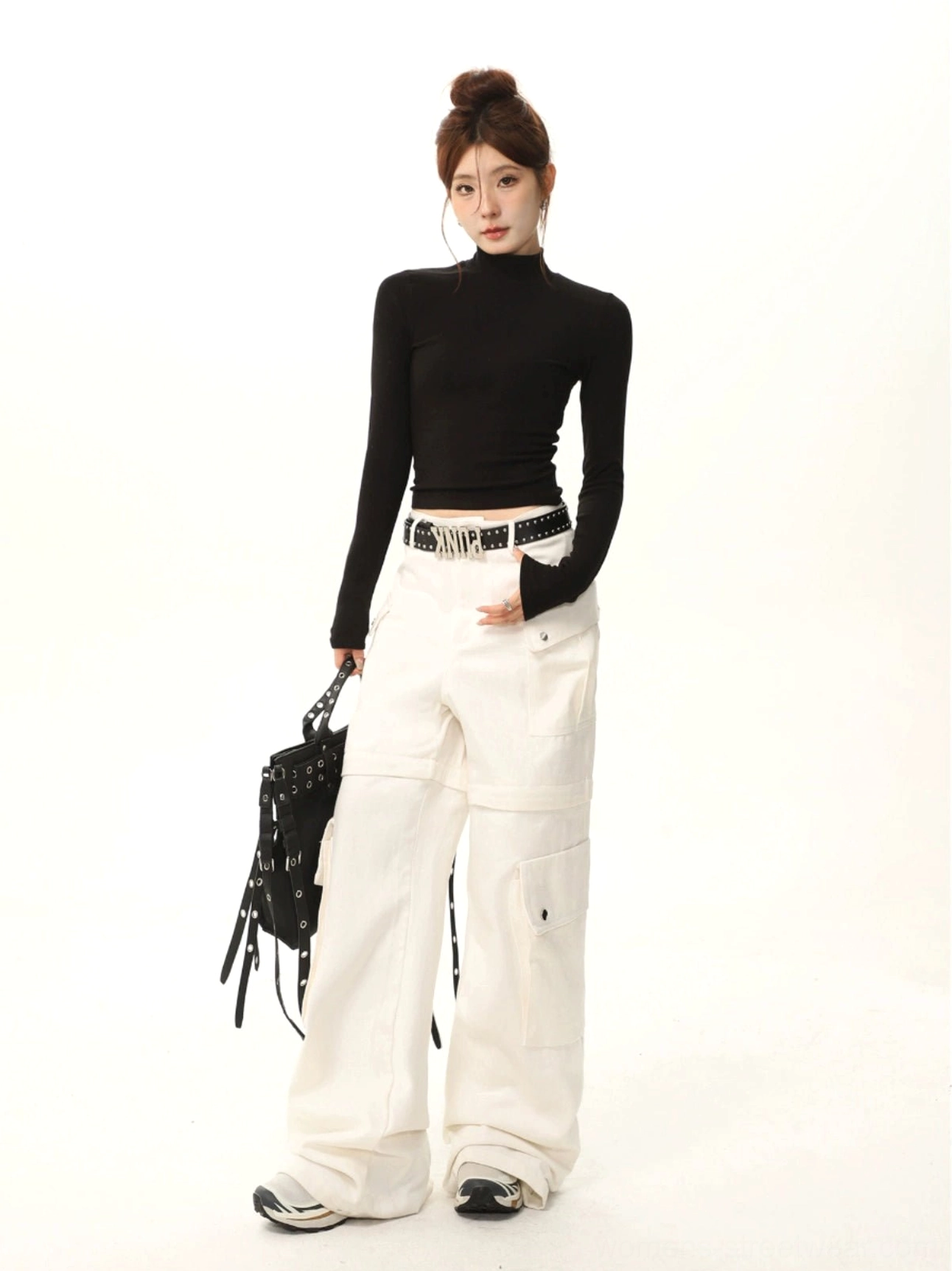 Black mock neck slim fit long sleeve streetwear top styled with white wide-leg cargo pants studded belt and black backpack