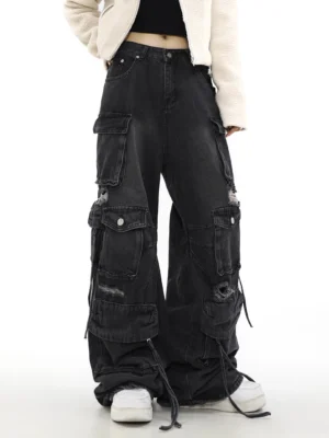 Front view of black multi-pocket baggy cargo jeans showing layered utility pockets, silver waistband hardware, and faded denim wash