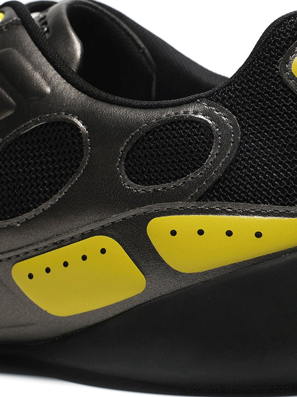 Close-up of the black mesh toe box and gunmetal overlay panels on retro colorblock sneakers with visible stitching and front strap