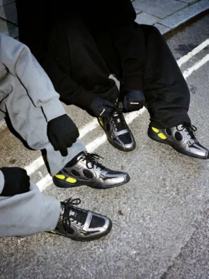 Black retro colorblock street sneakers worn with grey sweatpants and black track pants on an urban asphalt street in a Seoul-inspired outfit