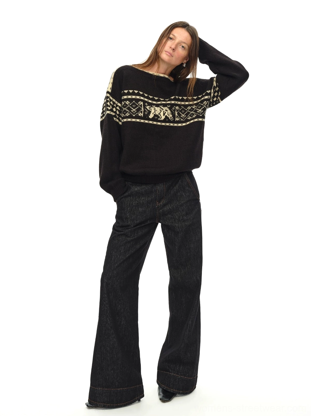 Black Nordic bear jacquard off-shoulder oversized knit sweater shown in left three-quarter full-body view with dark wide-leg jeans