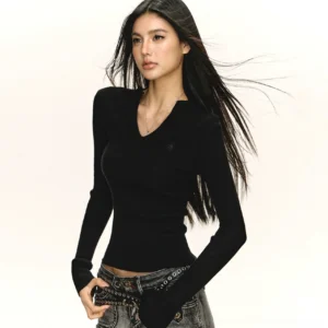 Black notched V-neck ribbed knit long-sleeve top with slim fitted silhouette styled with low-rise blue denim jeans