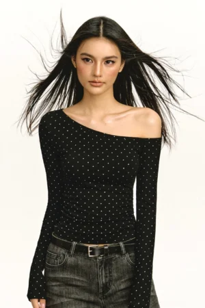 Black off-shoulder ruched long-sleeve top with subtle dot pattern styled with dark wash jeans