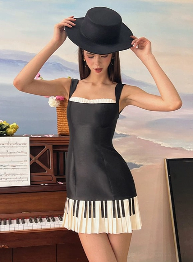 Black and off-white piano keys statement mini dress with ruffled square neckline and pleated hem styled beside a piano