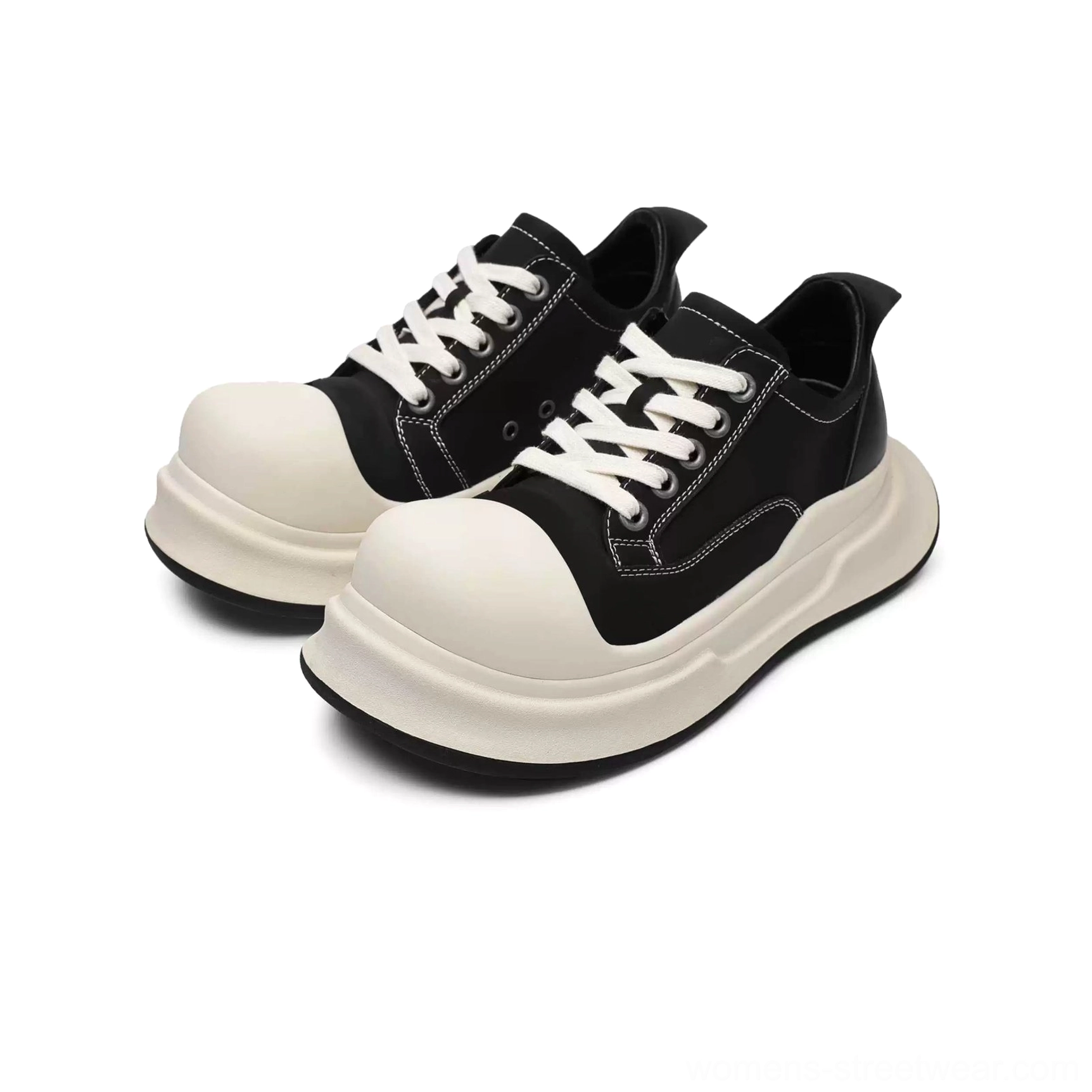 Front close-up of black and off-white platform sneakers showing the lace-up system, oversized round toe, contrast stitching, and layered thick sole