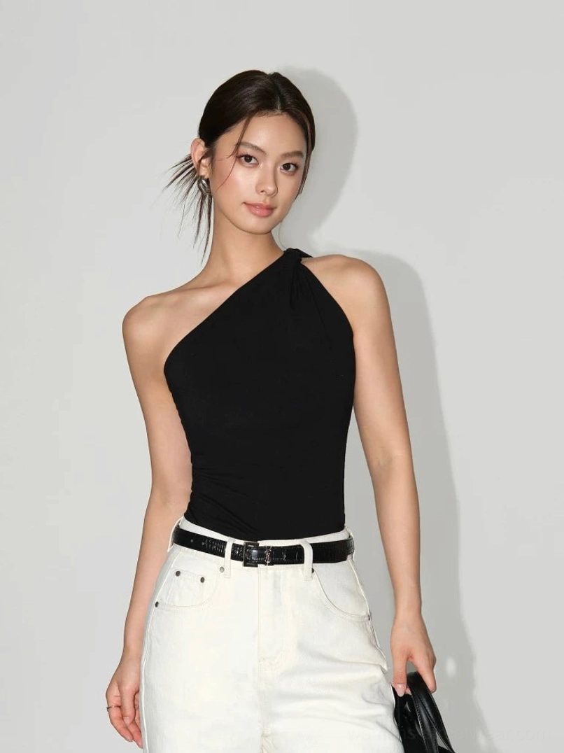 Black women's one-shoulder knit tank top with sculpted twisted neckline and slim fitted silhouette paired with white high-waisted trousers