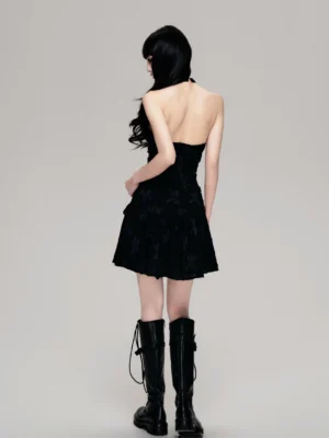 Black open back halter tiered ruffle mini dress styled with black combat boots rear view