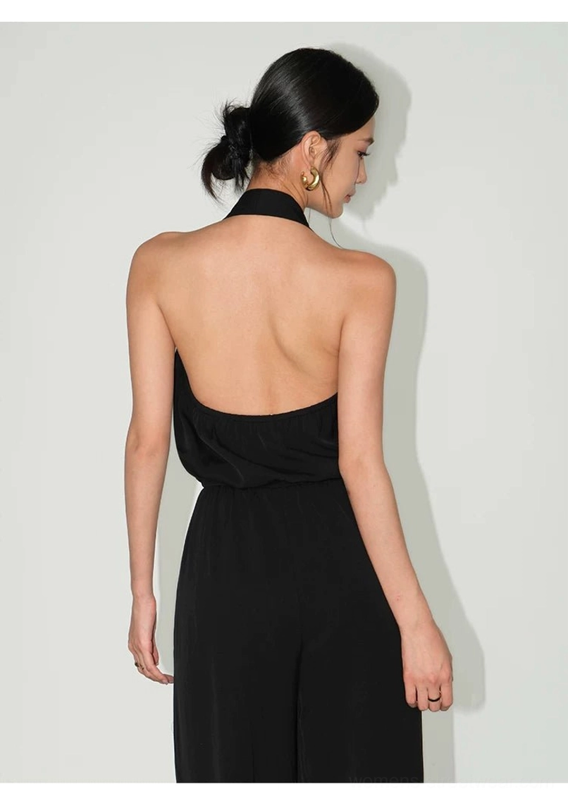 Back view of black draped halter wide-leg jumpsuit with open back, gathered waist, and flowing trousers