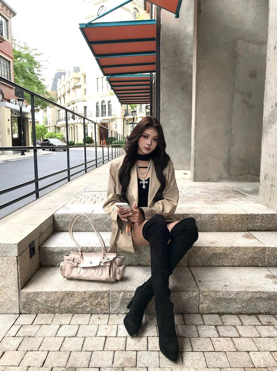 Model styling fitted black over-the-knee platform stiletto boots with a khaki coat on an urban stone stairway