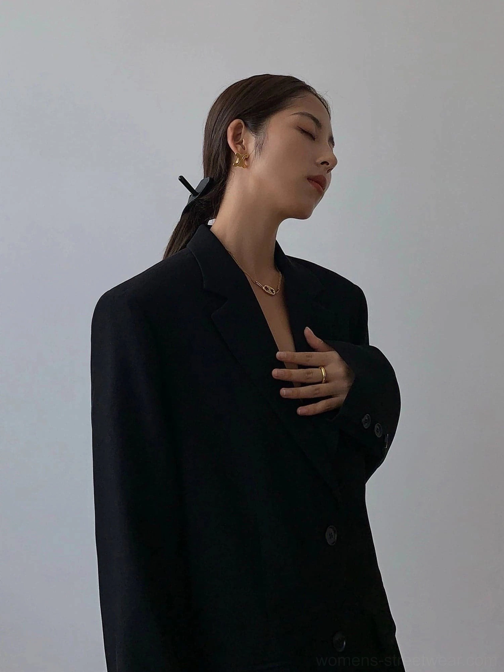 Black oversized blazer half side profile view notched lapel relaxed silhouette with gold jewelry