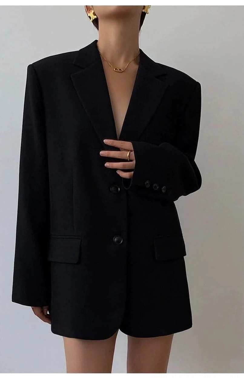 Black oversized blazer full front studio display with simple gold jewelry plain grey background