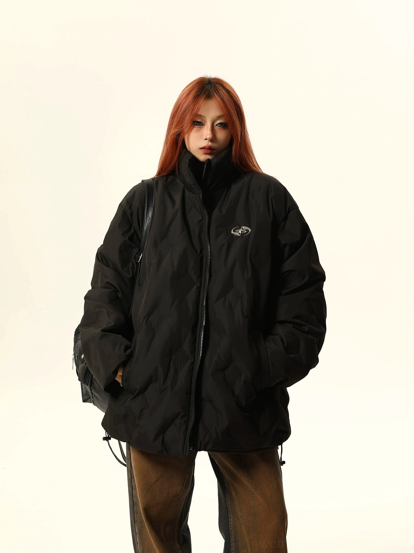 Side three-quarter view of a black oversized stand-collar quilted bomber jacket with front zipper and hidden pockets