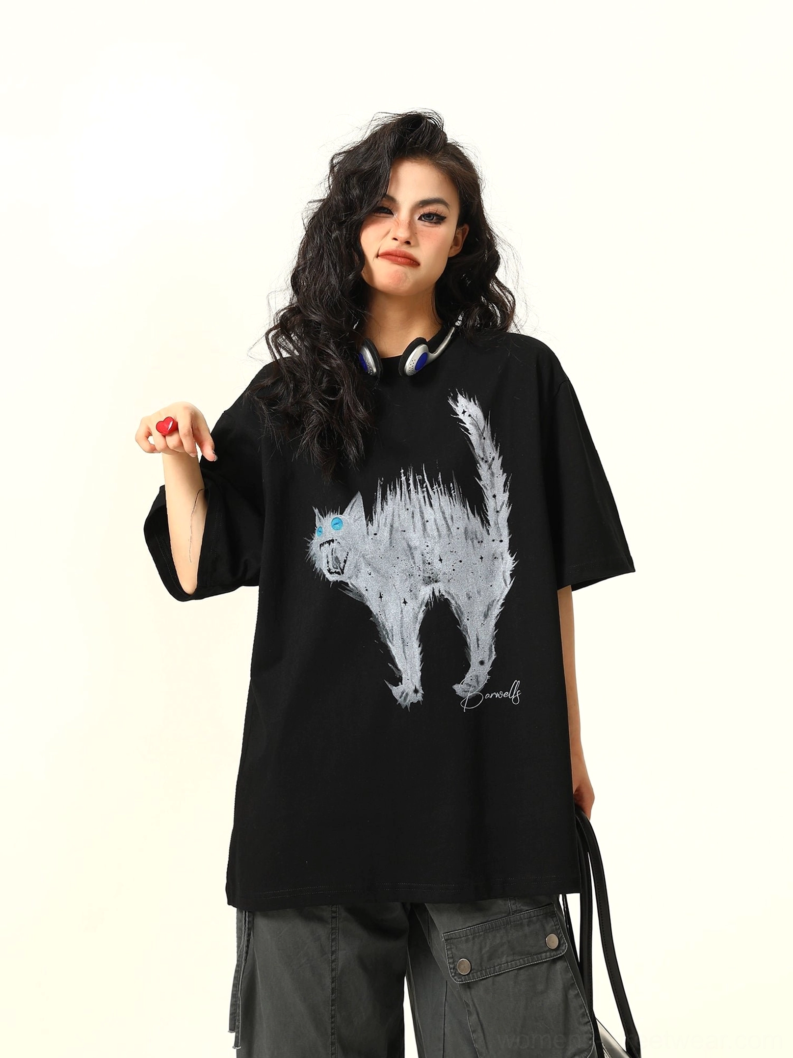 Three-quarter side view of a woman styling a black oversized cat graphic tee with dark cargo pants and a relaxed urban streetwear silhouette