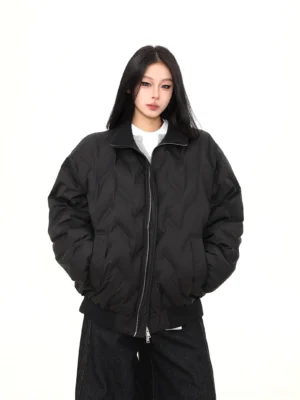 Front view of a relaxed oversized black puffer bomber jacket with chevron quilting, full zipper, stand collar, and ribbed cuffs