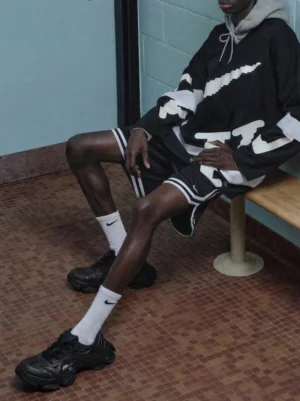 Black oversized chunky dad sneakers worn with white crew socks and athletic streetwear by a seated street style model