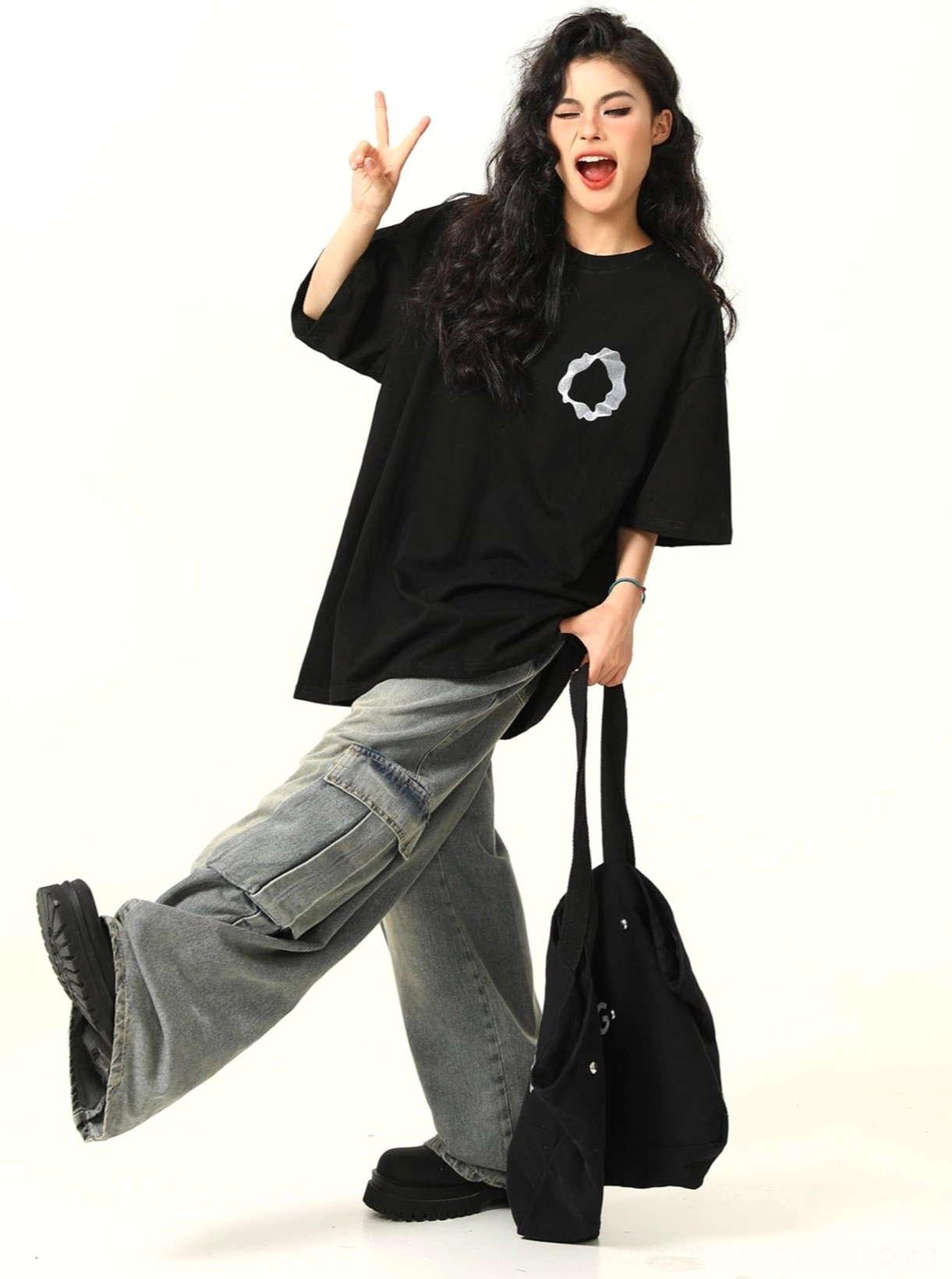 Dynamic front view of black oversized cotton streetwear tee with white abstract ring print and adjustable hem