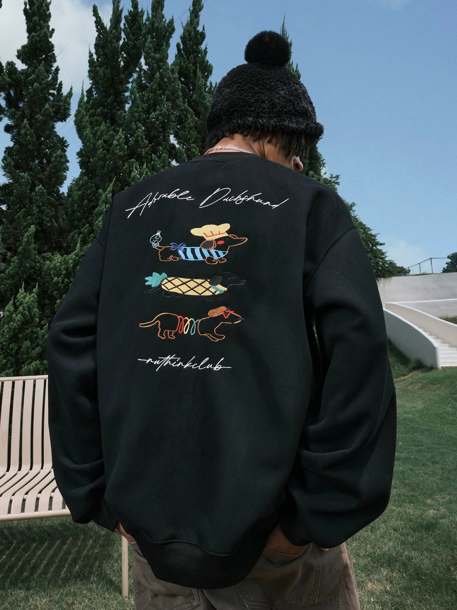 Full rear view of a black oversized dachshund crewneck sweatshirt with three embroidered-style dog graphics and relaxed sleeves