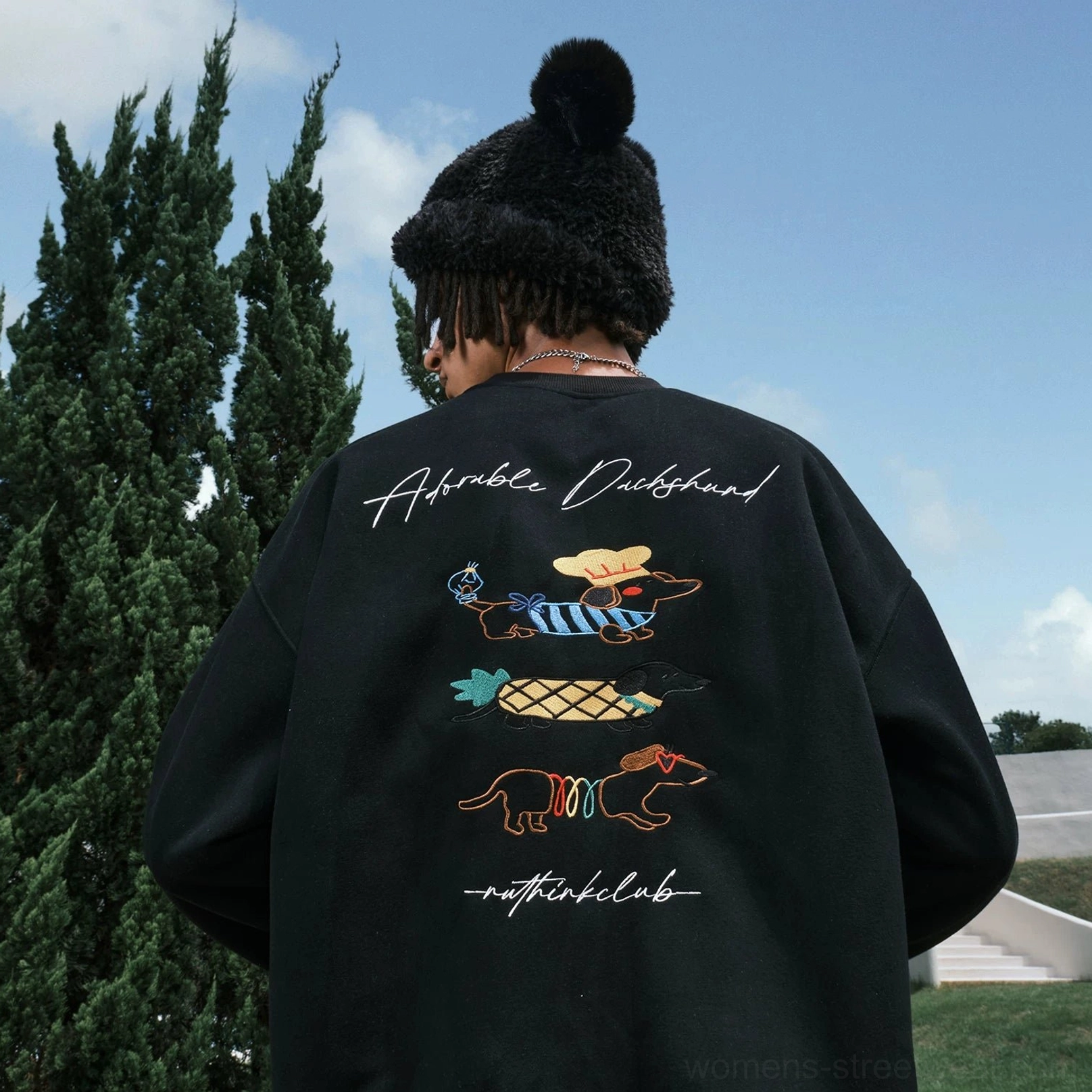 Black oversized dachshund graphic sweatshirt shown from the right rear side with colorful back artwork and long relaxed sleeves