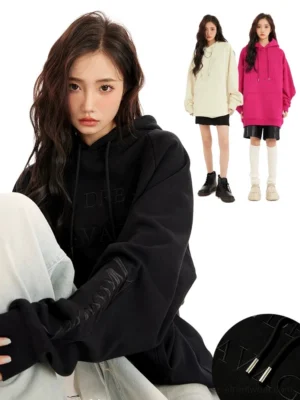 Black oversized embossed lettering hoodie shown in a relaxed side view with tonal graphics, metal-tipped drawstrings, and dropped shoulders