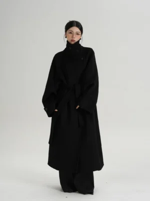 Black oversized women's wool blend coat with high funnel collar asymmetric wrap front removable waist belt raglan sleeves and wide leg streetwear styling