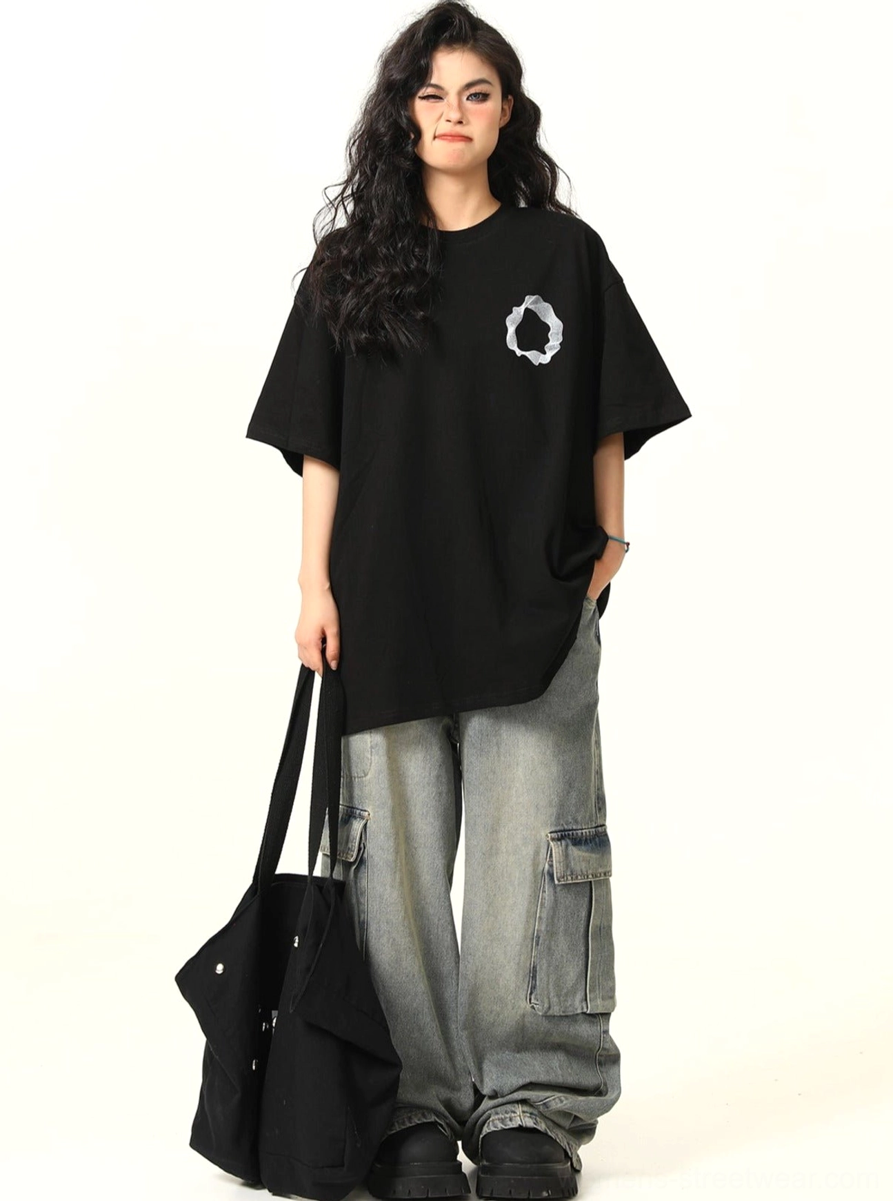 Black oversized graphic cotton tee with small white chest ring print styled with cargo denim jeans and tote bag