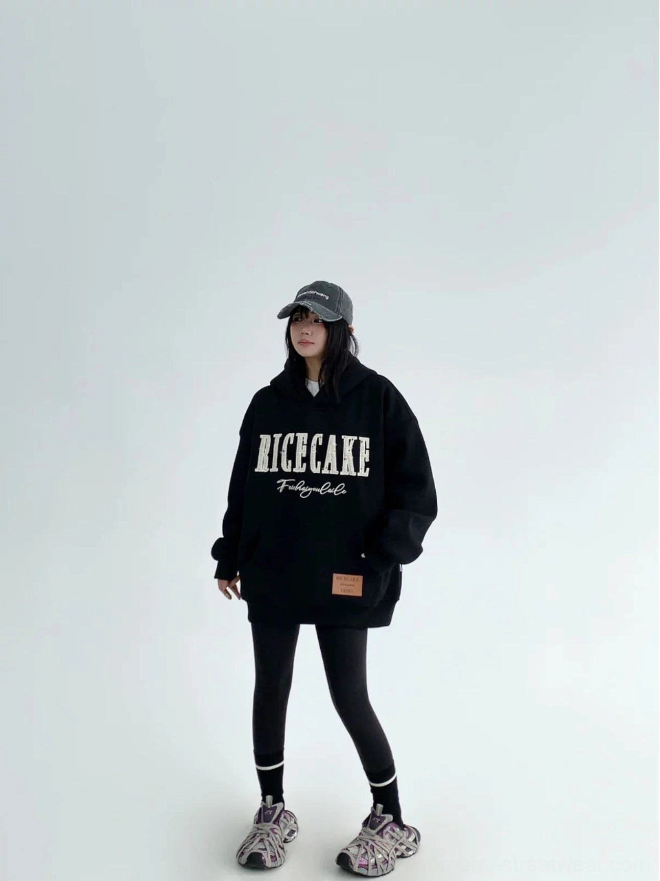 Full-body view of a black oversized graphic pullover hoodie with relaxed silhouette, front lettering, and sporty streetwear styling