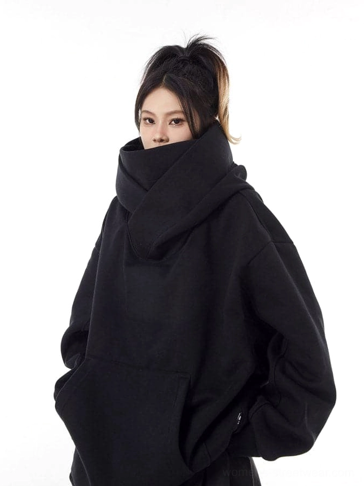 Front view of a black oversized high-neck hoodie with face-covering collar, soft fleece-like texture, and spacious kangaroo pocket