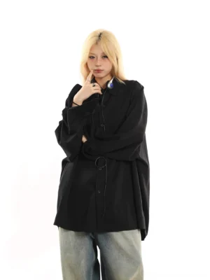 Black oversized loose button-down streetwear shirt shown from a three-quarter front angle with draped styling, wide-leg denim, and a hanging accessory detail