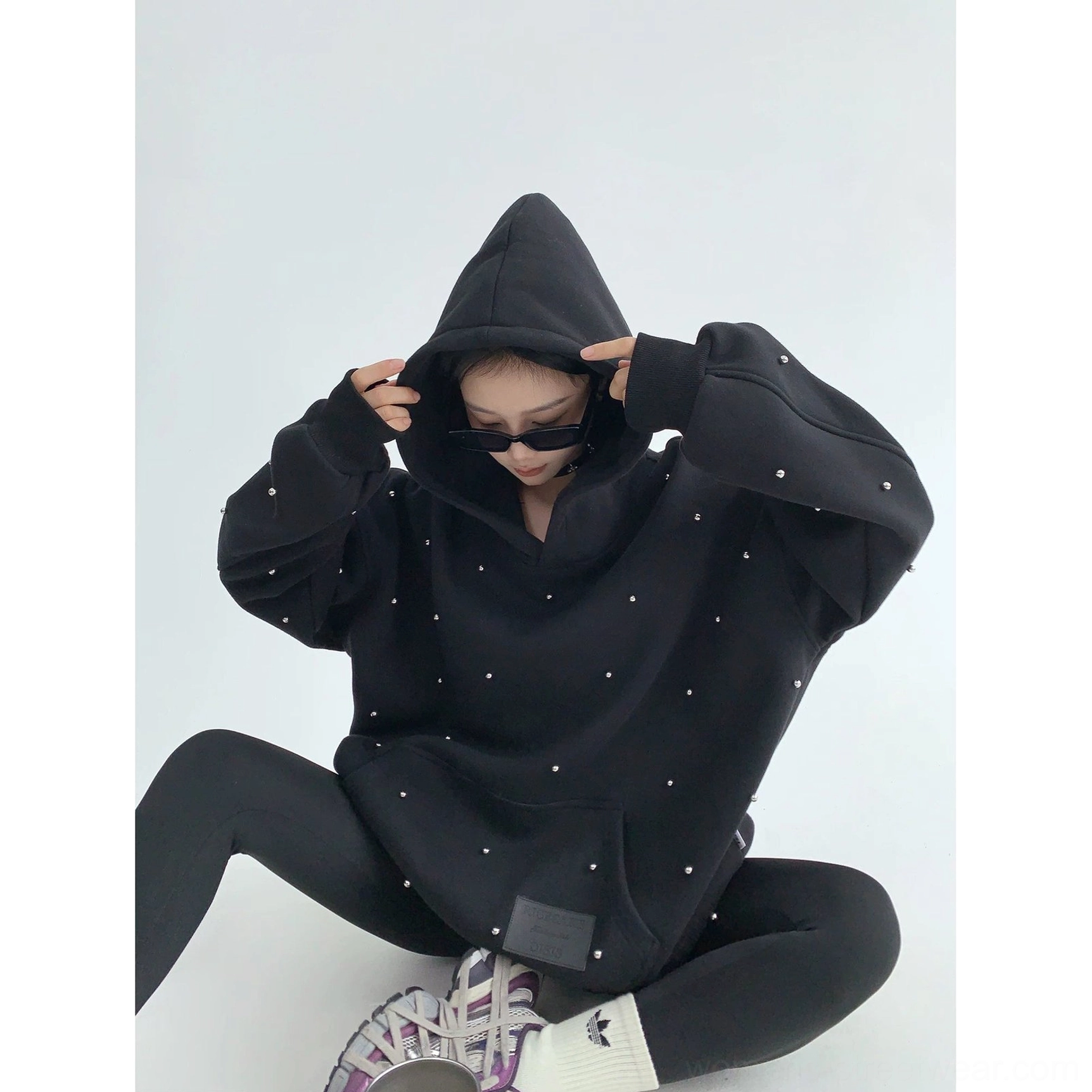 Black oversized pearl-studded streetwear hoodie worn with the hood adjusted, highlighting the dramatic hood and relaxed cocoon silhouette