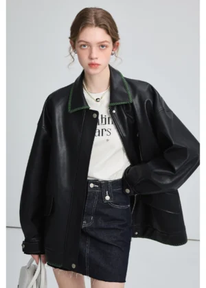 Model wearing a black oversized PU leather biker jacket with green contrast collar stitching in a relaxed streetwear outfit