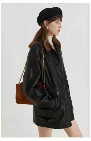 Side profile of a woman wearing a black oversized PU leather moto jacket with retro utility pockets and adjustable hem tabs