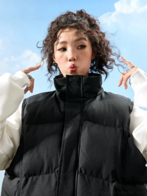 Black oversized puffer vest with high stand collar and quilted panels shown in a front close-up