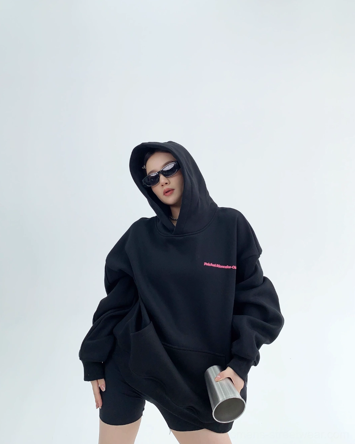 Jet black oversized pullover hoodie front view with hood up pink chest graphic kangaroo pocket and ribbed cuffs