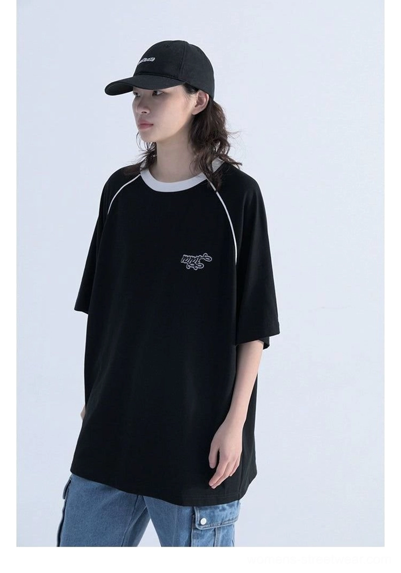 Front three-quarter view of black oversized contrast raglan sleeve streetwear T-shirt with white collar, embroidered chest detail, and cargo denim styling